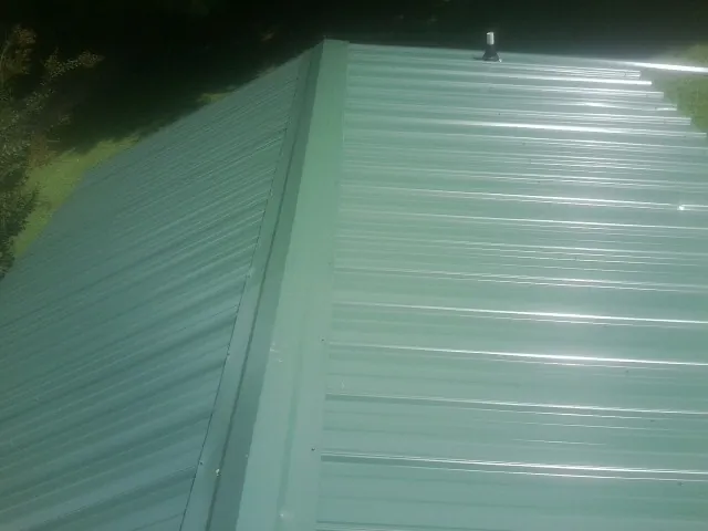 New green metal panels meeting at the ridge of a roof — Flat Roof Repair work by our crew in District Heights