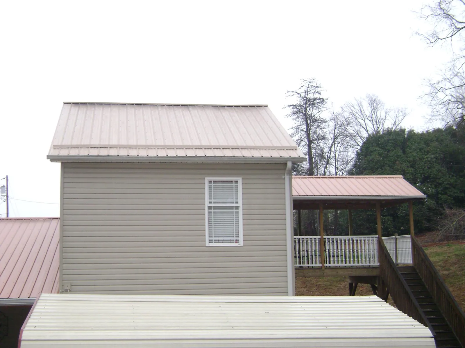Tan metal roofs on a two story addition and attached porch, from a Roof Replacement job in District Heights