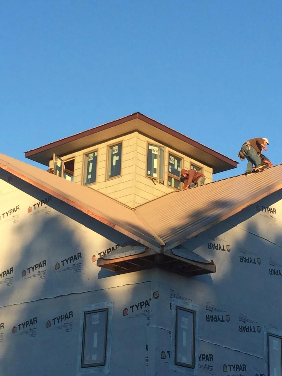 Roofers working around a rooftop cupola on a new metal roof at sunset — Roof Waterproofing in District Heights by Roofing Brothers